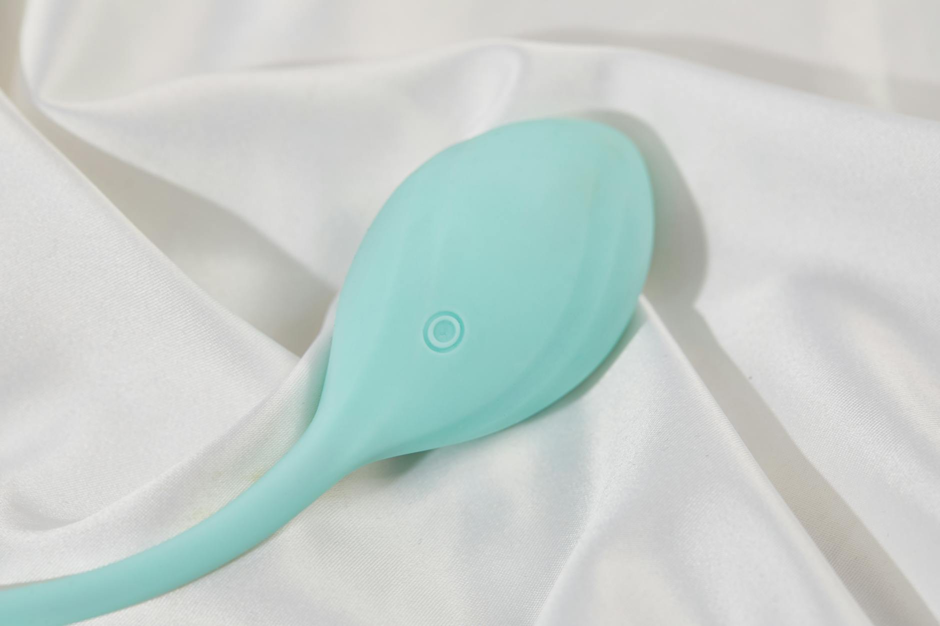 A sleek teal lemon vibrator resting on white silk, ready for pleasure recovery