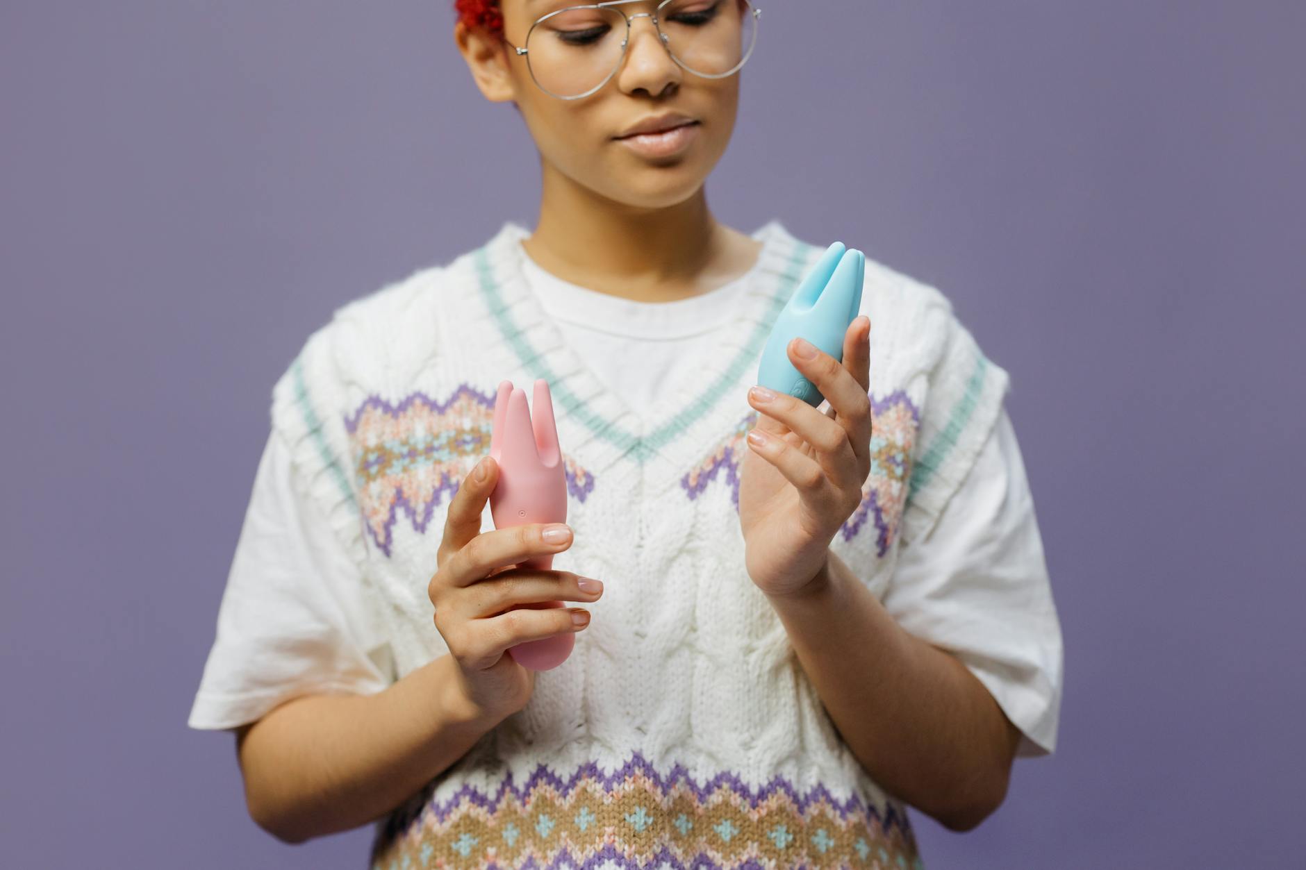 Mulher segurando um vibrador clitoral lemon com expressão pensativa, considerando o uso sobre a roupa