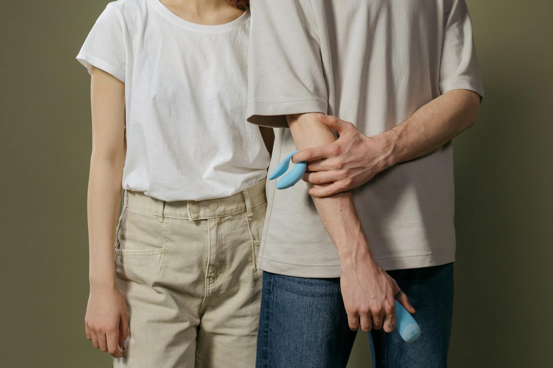 A hand holding a blue silicone clitoral vibrator against a purple background, symbolizing self-pleasure and intimacy.