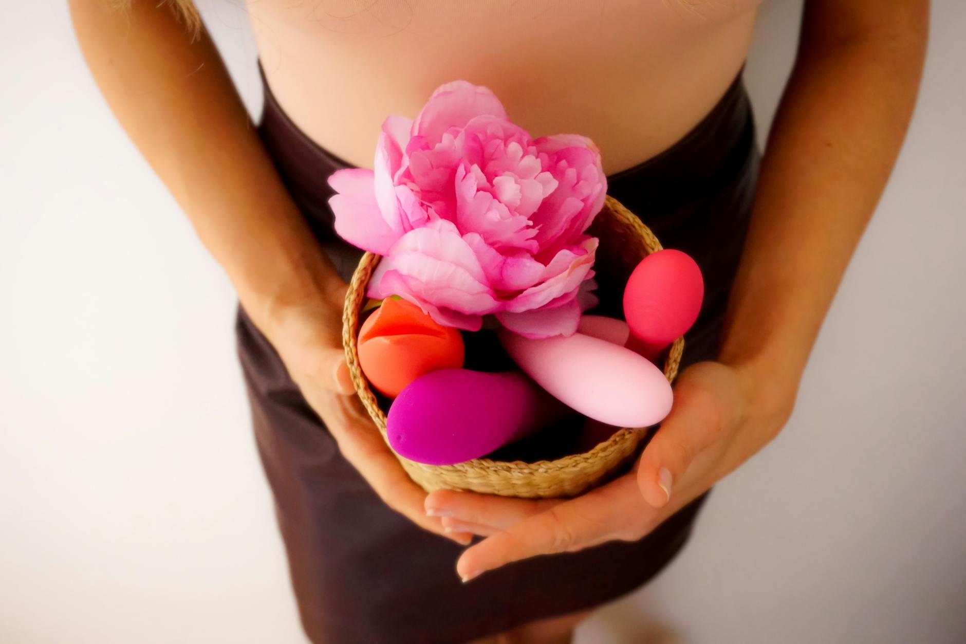 Close-up of hands holding a personal clitoral vibrator, representing gentle pleasure during pelvic recovery